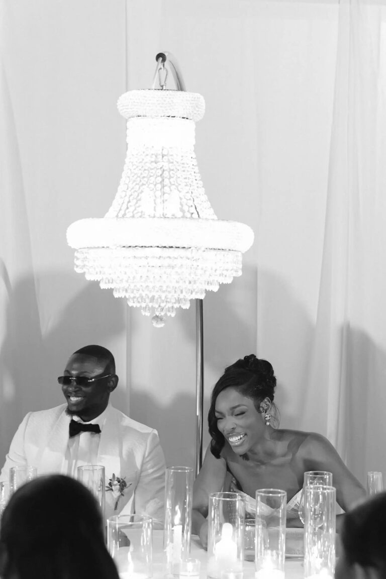 Guests seated beneath a crystal chandelier at the wedding dinner, Cygnus Events