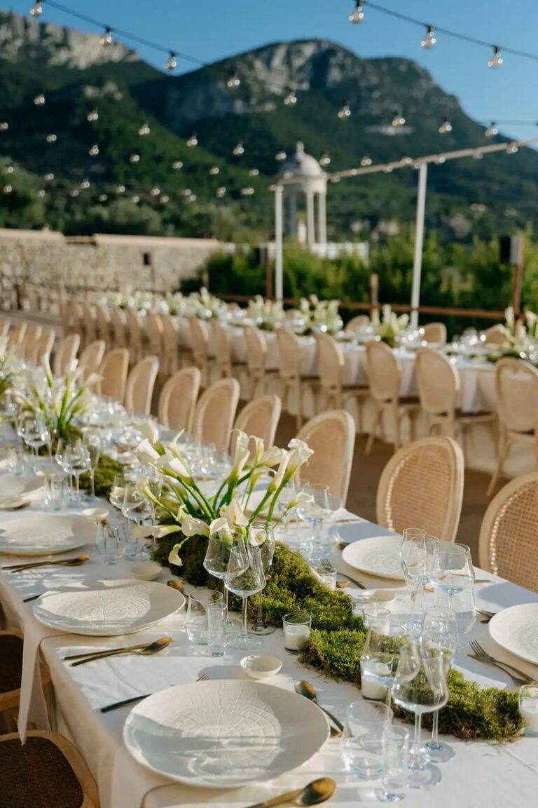 A long table with cane chairs and moss runner set against the Tramuntana mountains, Cygnus Events