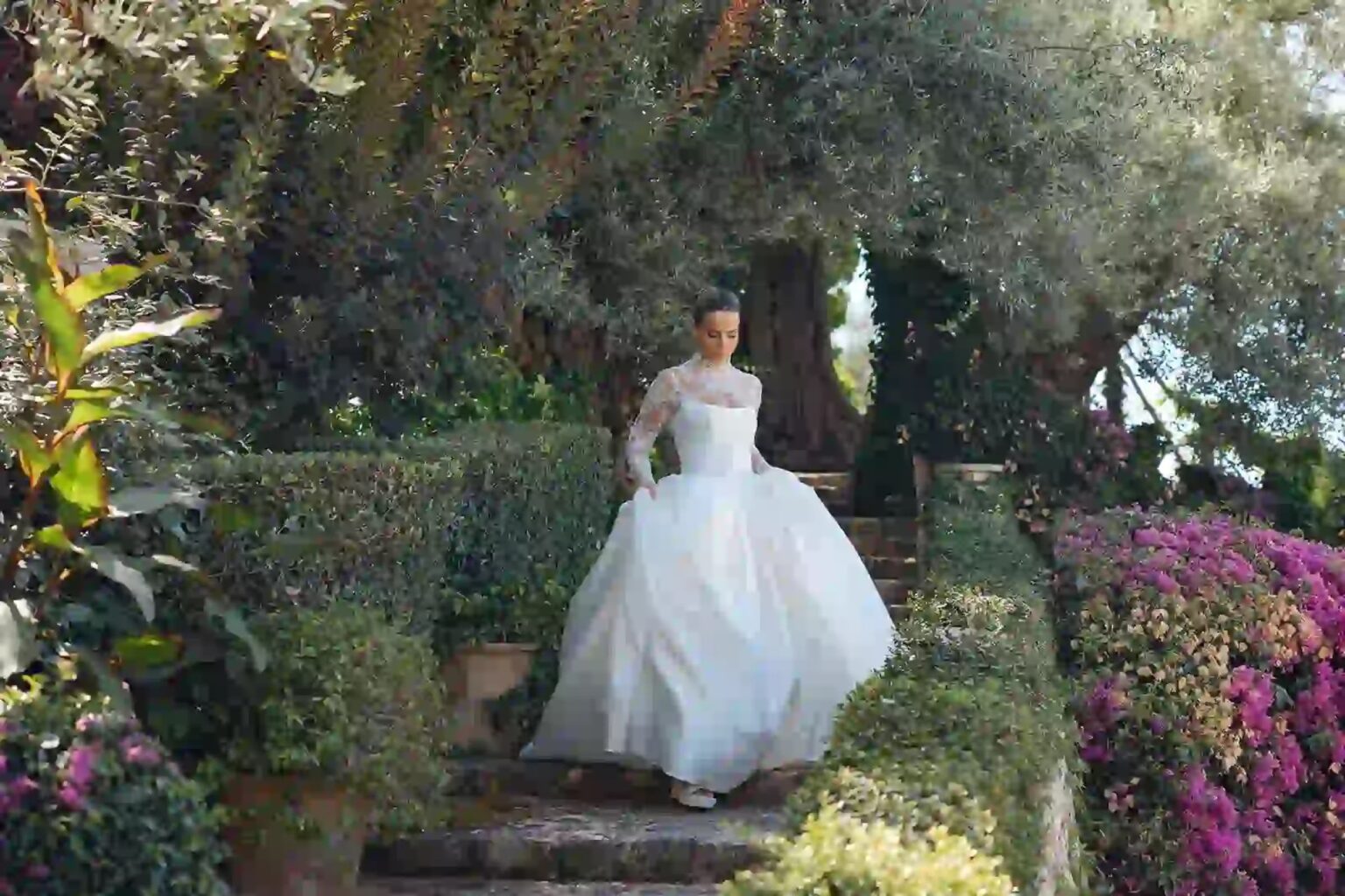 A bride in a satin gown walking through a terraced garden, Mallorca