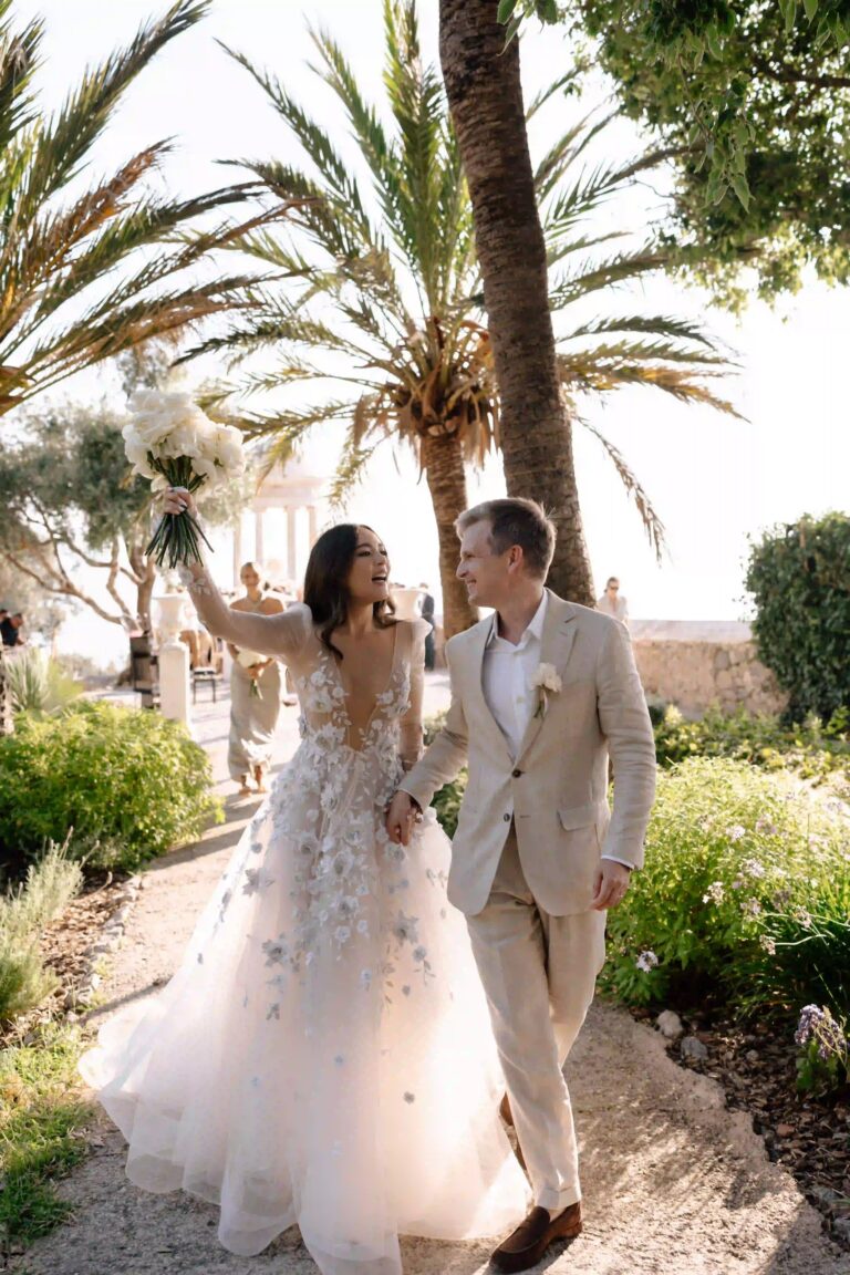 A couple walking through a garden of palms with a bouquet raised, Cygnus Events