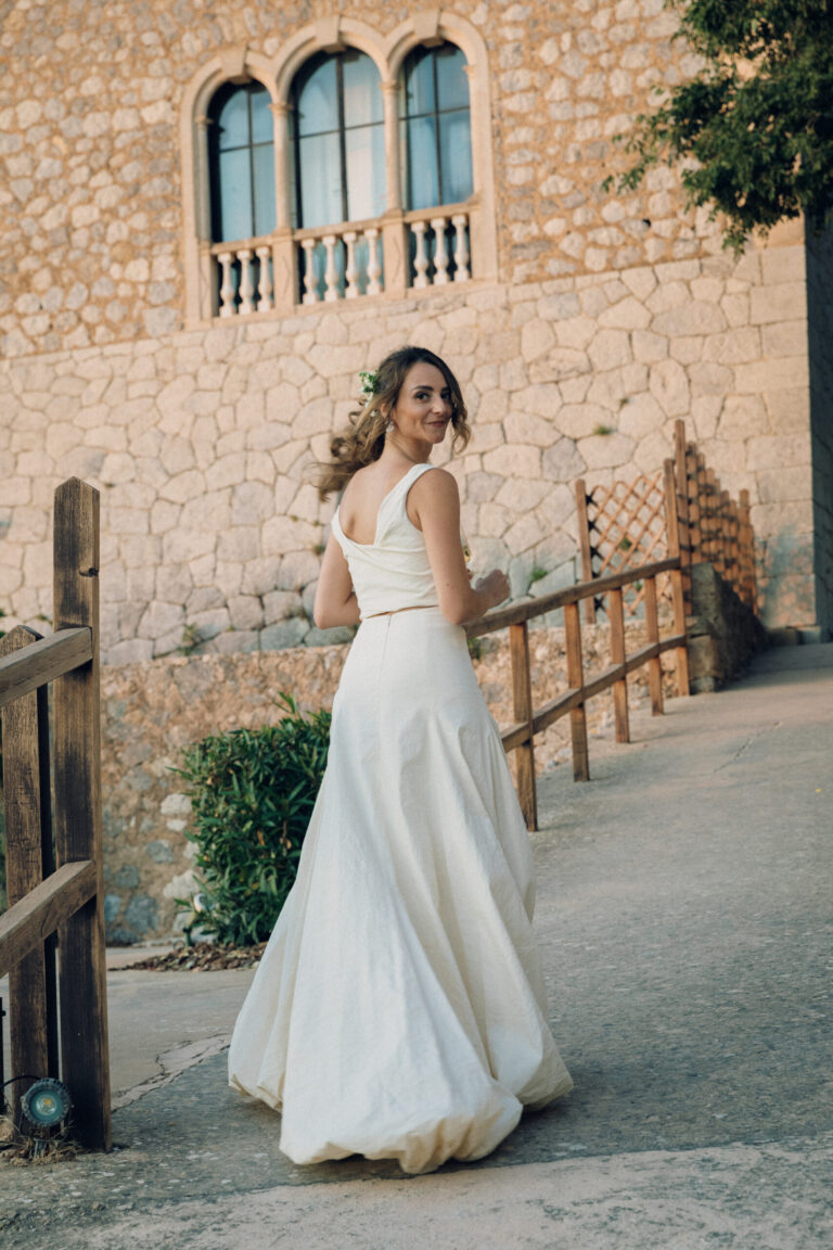 A bride in a two-piece gown on a stone path beneath a finca, Cygnus Events