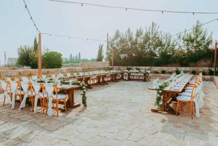 Long banquet tables with rustic chairs under festoon lights, Cyprus Wedding Touches