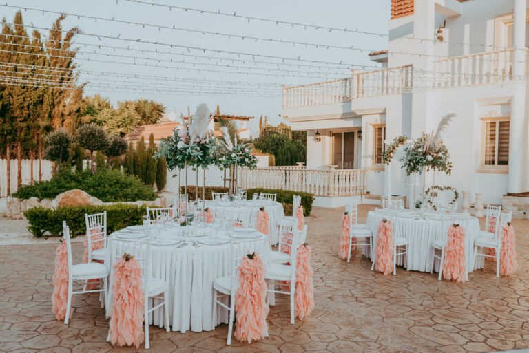 Round tables with peach ruffled chair covers in a villa courtyard, Cyprus Wedding Touches