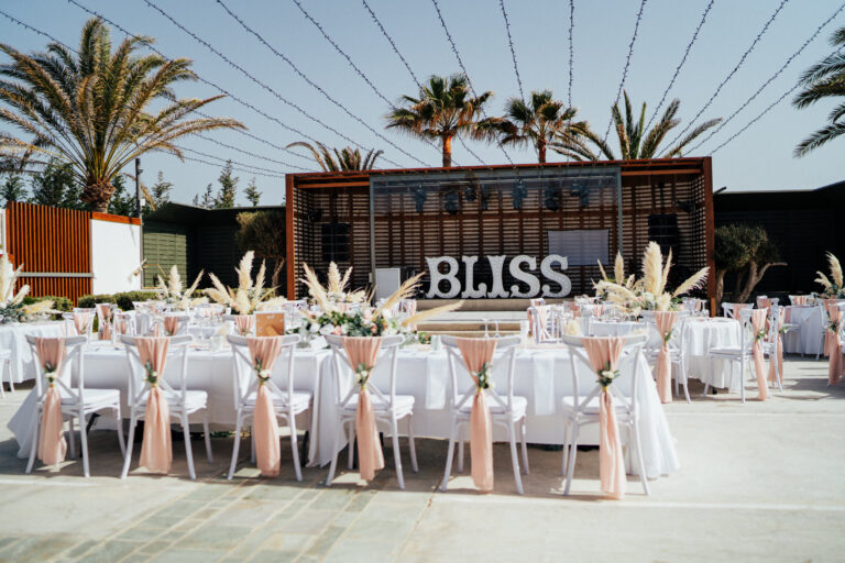 Reception tables with blush chair sashes and a BLISS sign, Cyprus Wedding Touches