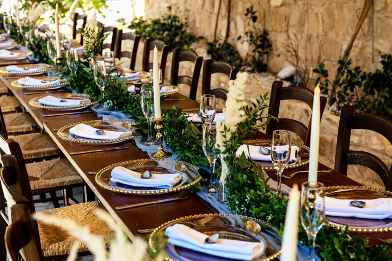Rustic long table with candles and greenery under a stone pergola, Cyprus Wedding Touches