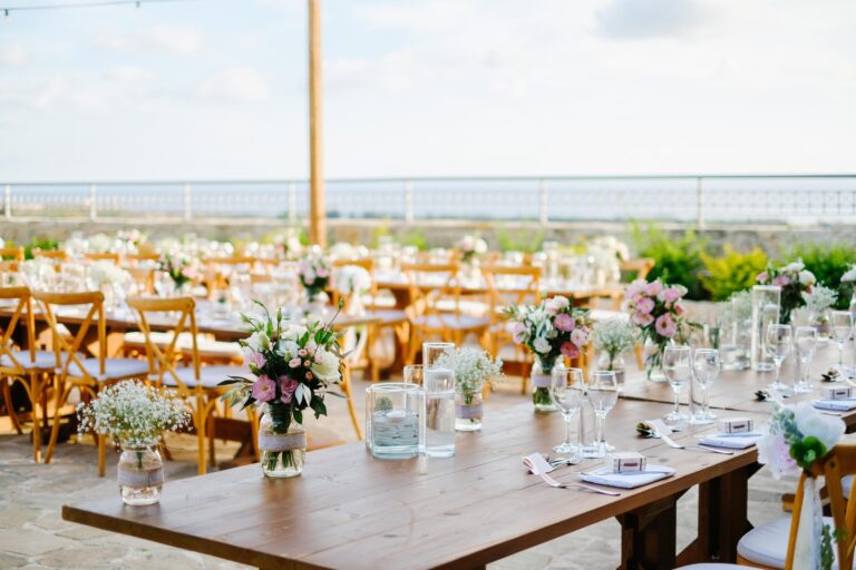 Wooden tables with pink and white posies on a stone terrace, Cyprus Wedding Touches