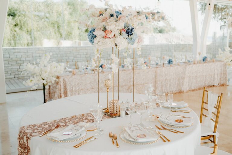 Round table with a tall floral centrepiece and gold chairs, Cyprus Wedding Touches