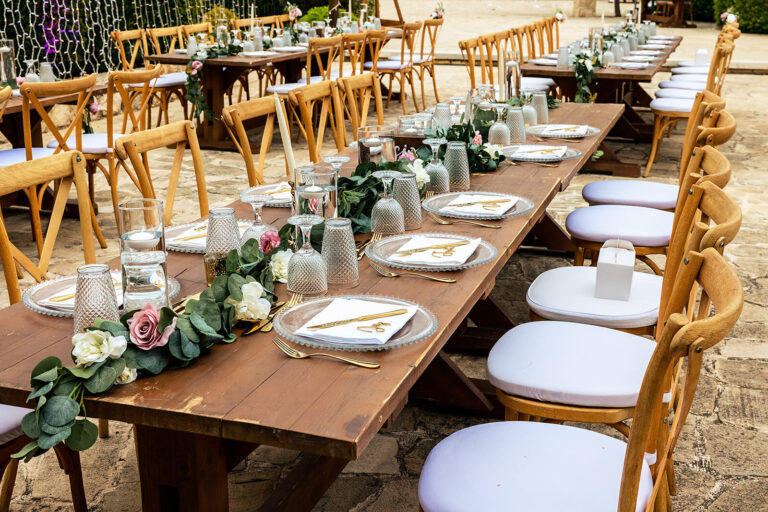 Long table with cross-back chairs, garland and posies, Cyprus Wedding Touches