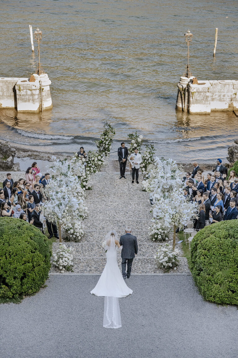 Seen from above: a bride walking down a flower-lined aisle towards the lake, Lake Como, Daniele Vertelli Photography