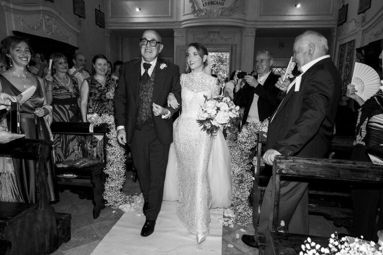 The bride walked up the aisle of a country church in Chianti, guests fanning themselves, black and white, Daniele Vertelli Photography