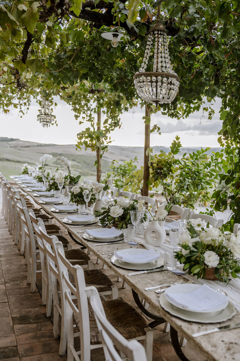 A long table under a vine pergola with a chandelier, The Lazy Olive, Tuscany, Daniele Vertelli Photography