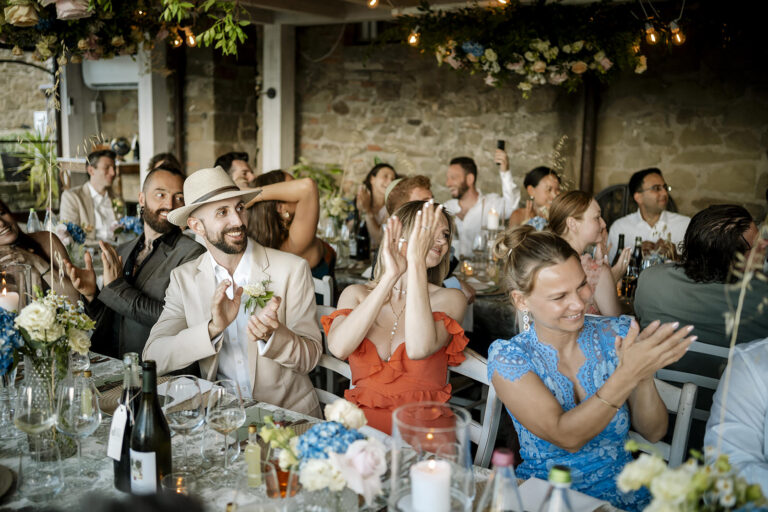 Guests laughing and applauding at dinner, a Jewish wedding in Umbria, Daniele Vertelli Photography