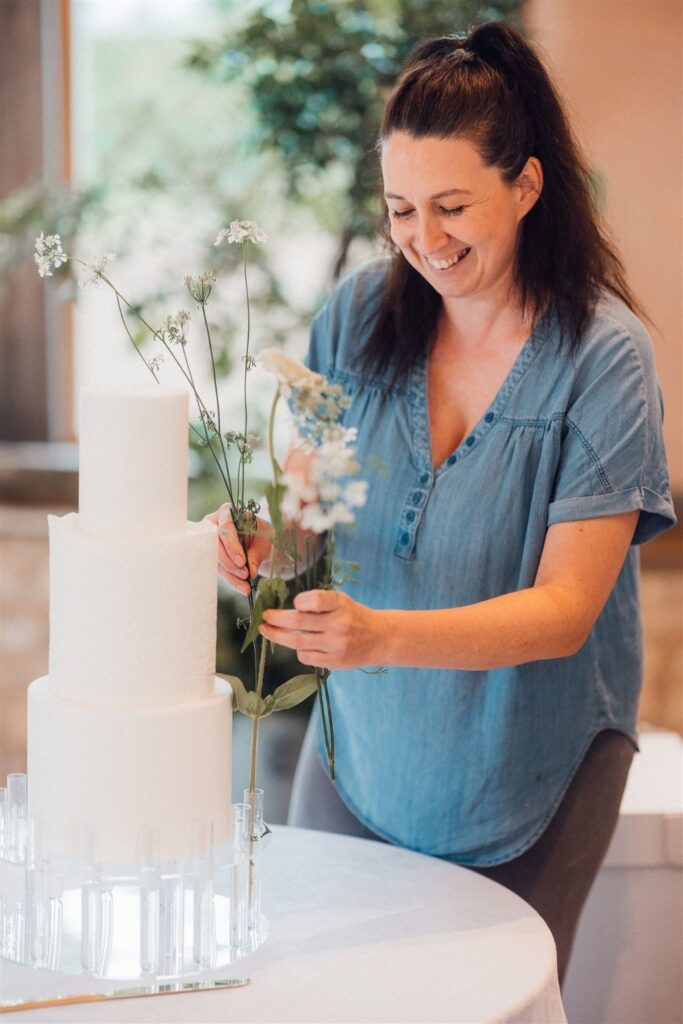 Danielle placing sugar flowers on a wedding cake, Danielle's Cakes Pershore