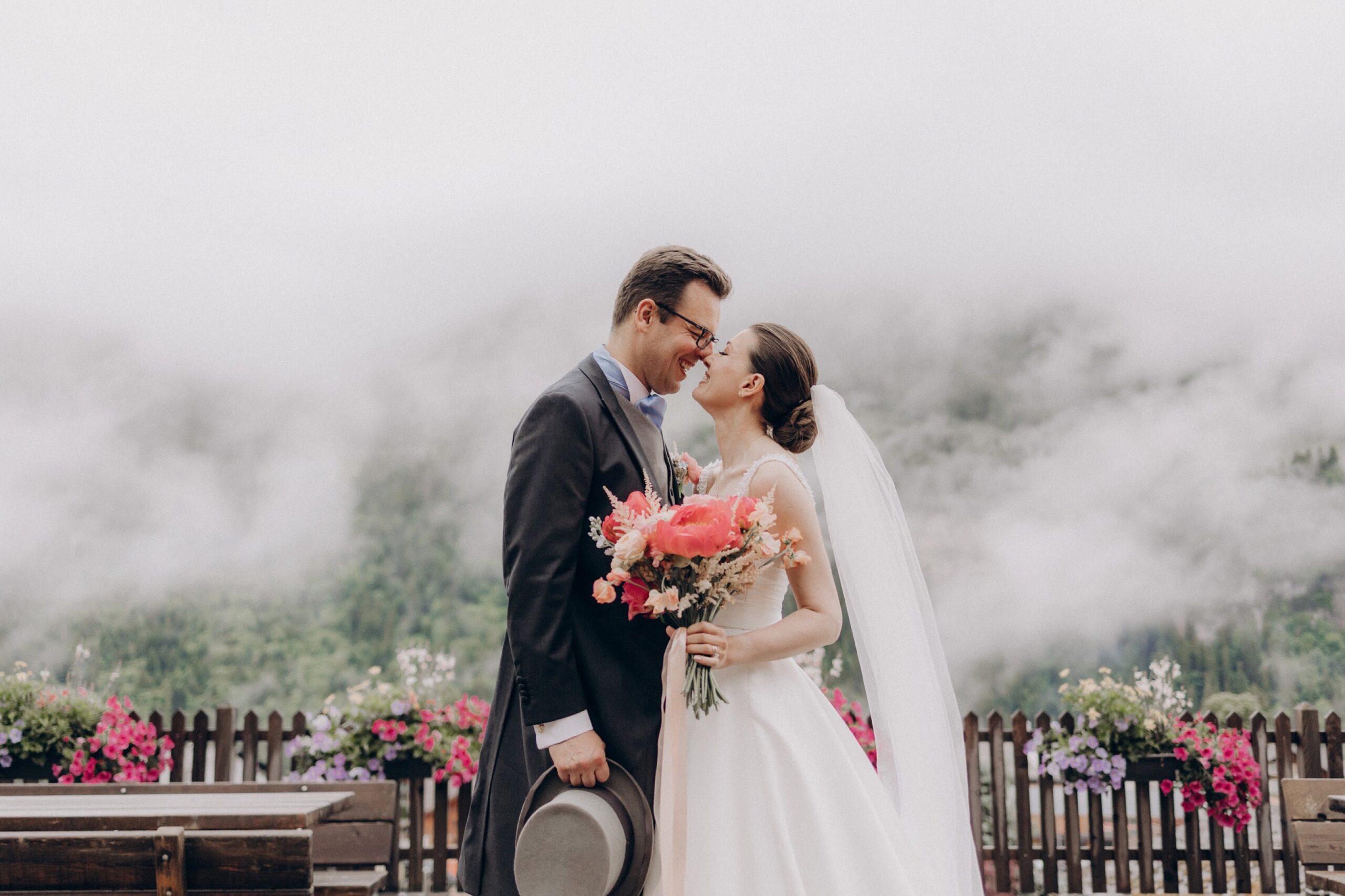 Couple embracing on a flower-lined balcony in the mountain mist, Champéry, Switzerland, Daria Events and Weddings
