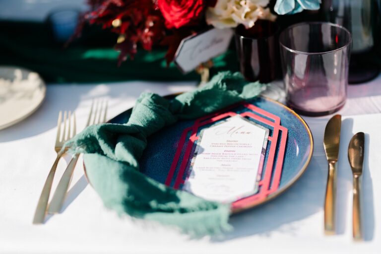 Place setting with menu card, green napkin and burgundy florals, Daria Events and Weddings