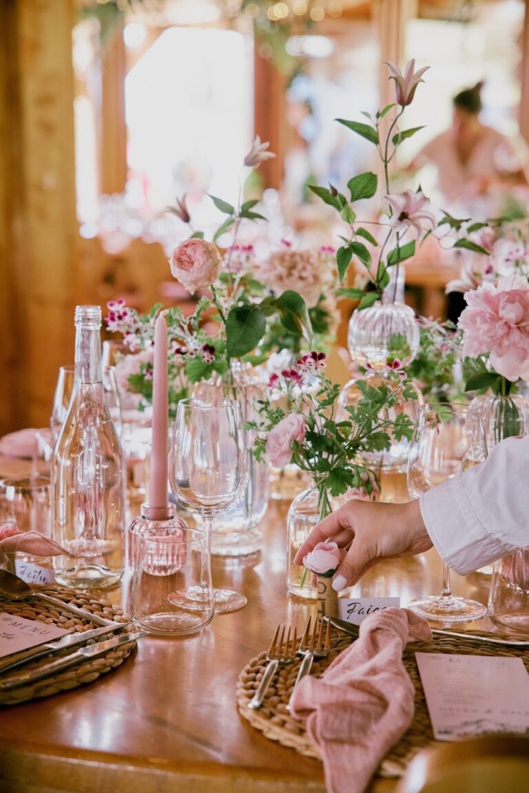 Table with pale pink flowers, glassware and napkins in a timbered room, Daria Events and Weddings