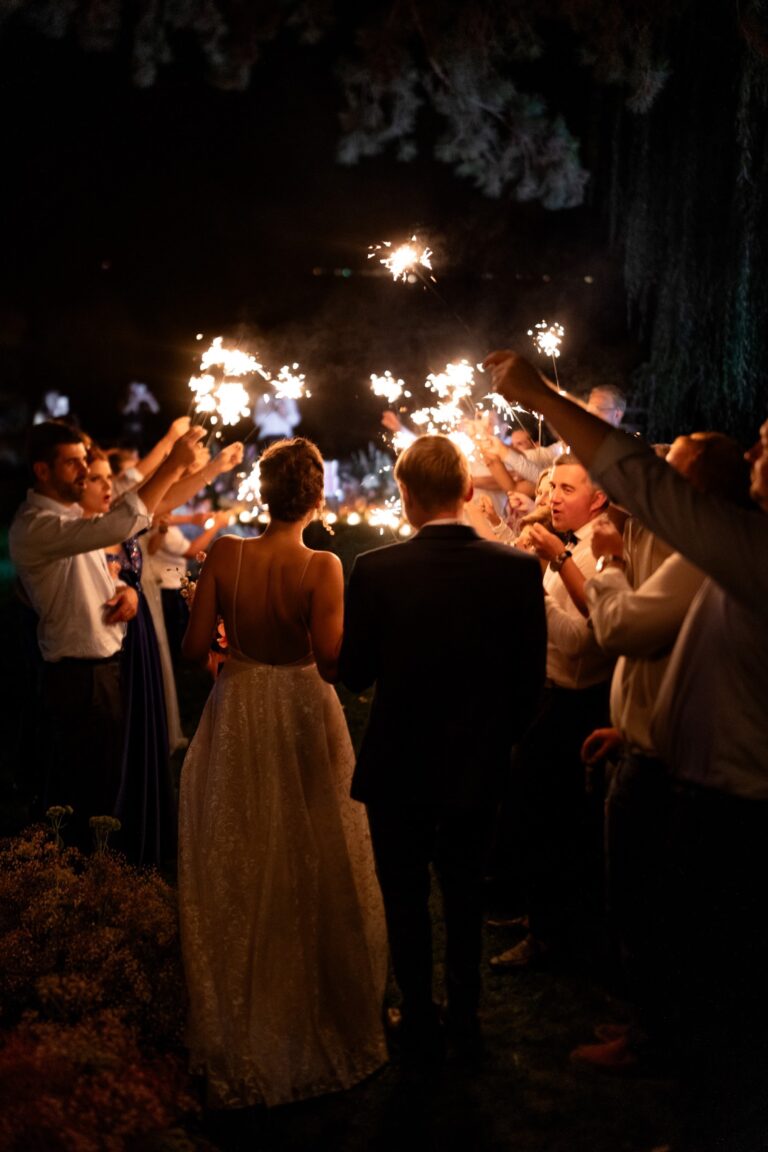 Couple surrounded by guests holding sparklers at night, Daria Events and Weddings