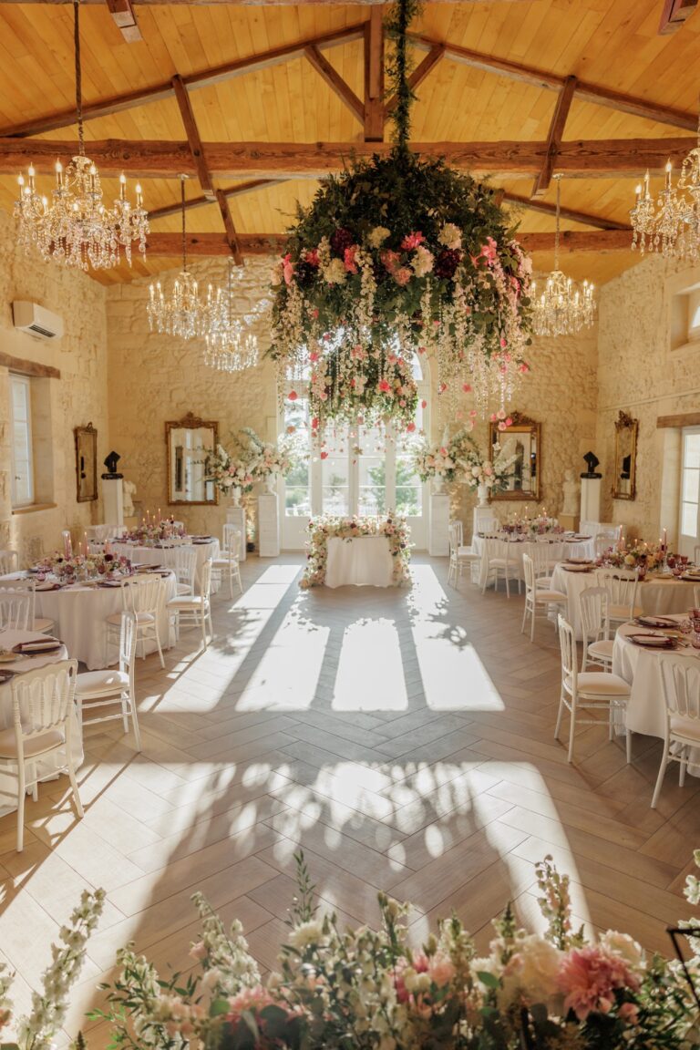 Stone reception hall with a hanging floral chandelier and long afternoon light, Daria Events and Weddings
