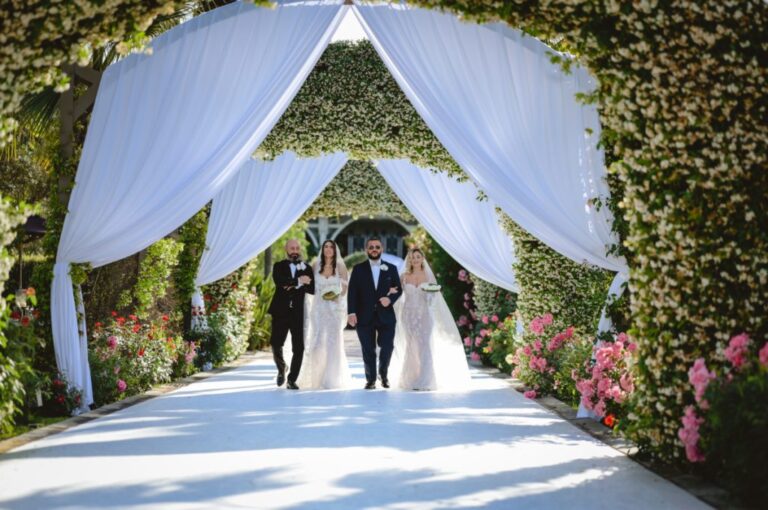 Guests walking in through white drapes and an arch of climbing flowers, Dario Varsalona