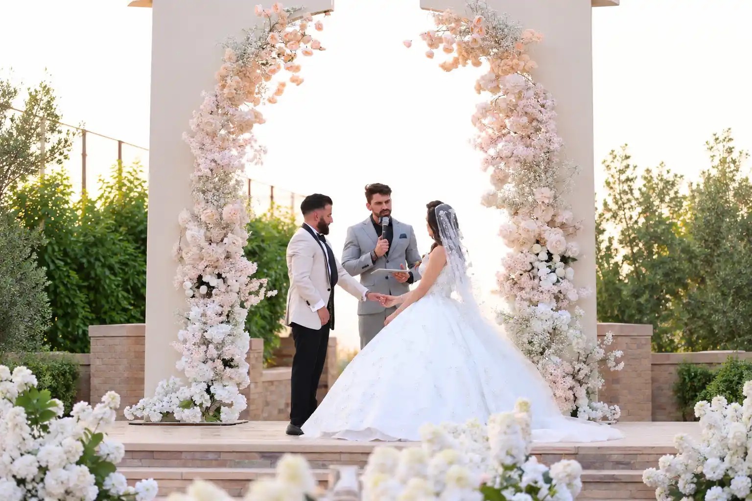 Couple at a floral arch with the celebrant