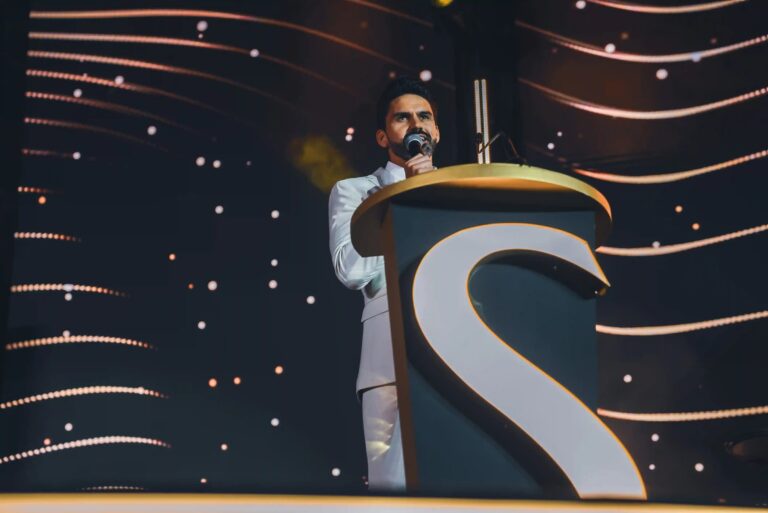 MC at a podium on a lit stage