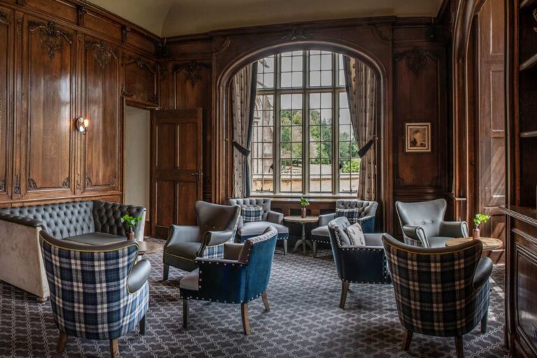 The panelled Towers Bar lounge with checked armchairs and a tall arched window, De Vere Horsley Estate
