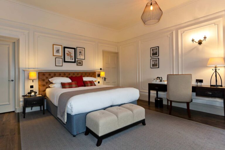 A Junior Suite in Horsley Towers with panelled walls and a padded headboard, De Vere Horsley Estate