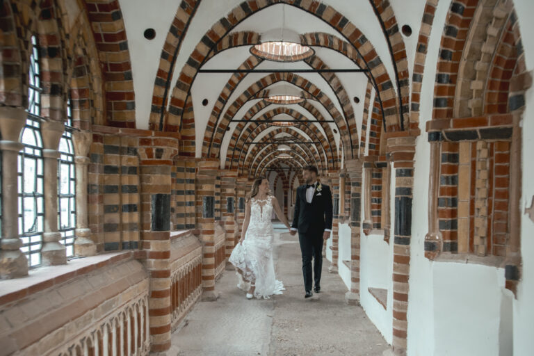A couple walking through the arched cloisters, De Vere Horsley Estate