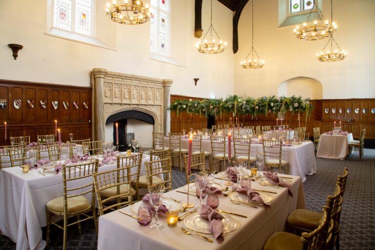 Long tables with candles and blush napkins for a wedding breakfast in the Great Hall, De Vere Horsley Estate