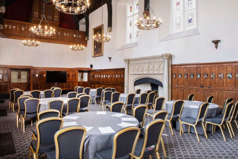 Round tables laid in the oak-panelled Great Hall beside the stone fireplace, De Vere Horsley Estate