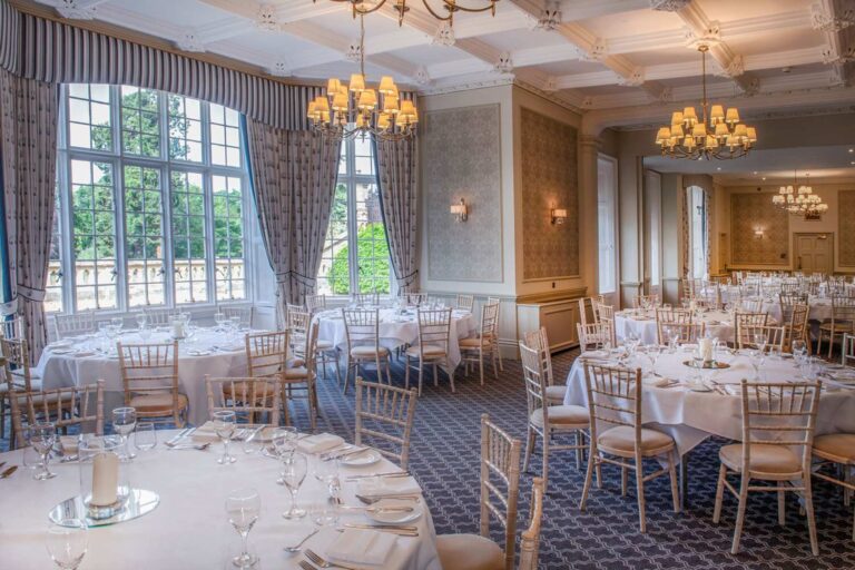 The Sopwith Suite laid with round tables under chandeliers and tall windows, De Vere Horsley Estate