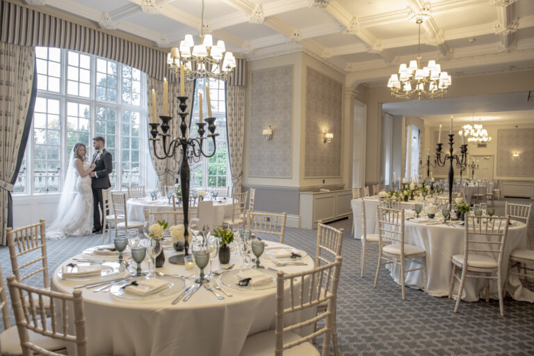 A couple among the dressed round tables in the Sopwith Suite, De Vere Horsley Estate