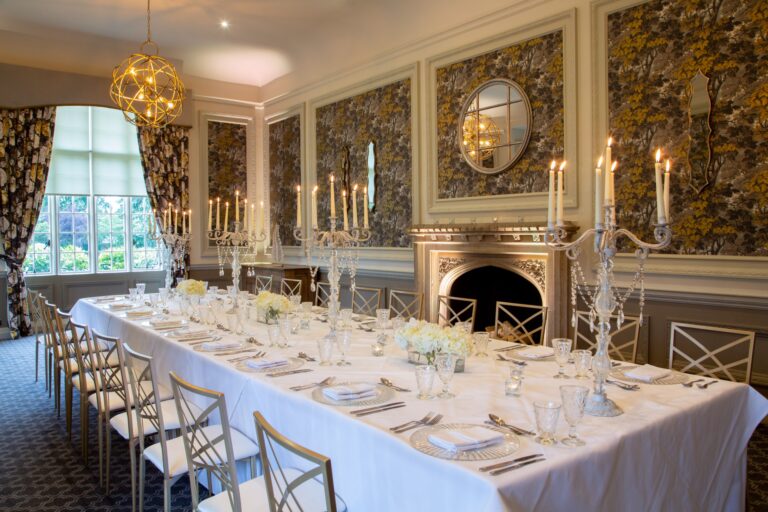 A long candlelit table set in the 1820 Room in front of the marble fireplace, De Vere Horsley Estate