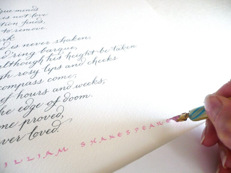 A dip pen writing a line of poetry in grey ink with red lettering beneath, Denise Hagon Calligrapher
