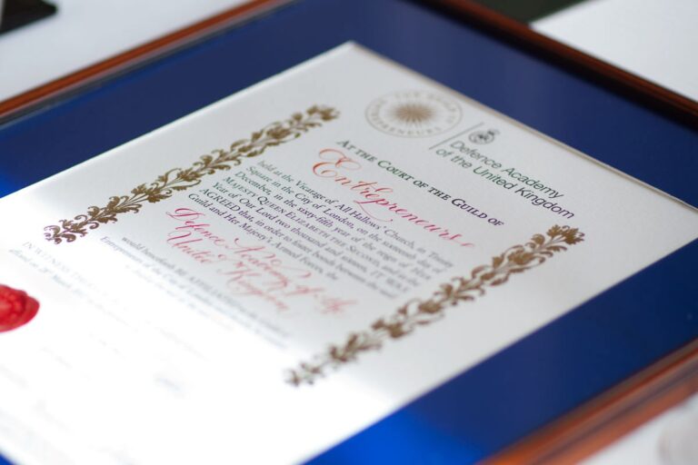 A framed certificate in calligraphy with gold illumination and a red wax seal, Denise Hagon Calligrapher