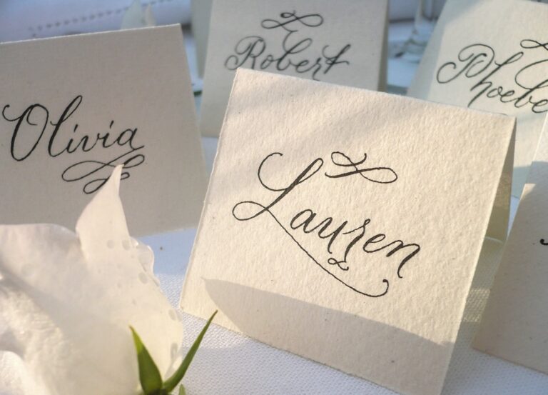 Calligraphy place cards standing on a table with a white flower, Denise Hagon Calligrapher