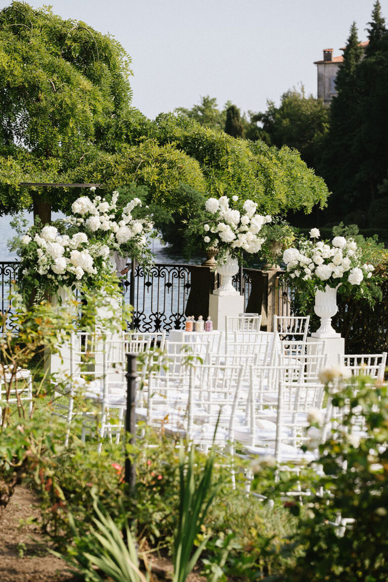 A garden ceremony set with white flowers and white chairs above Lake Maggiore, Denise More