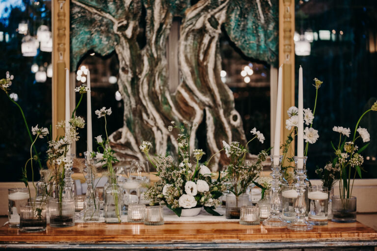 Candles and white flowers set before an olive trunk at the dinner in Puglia, Denise More