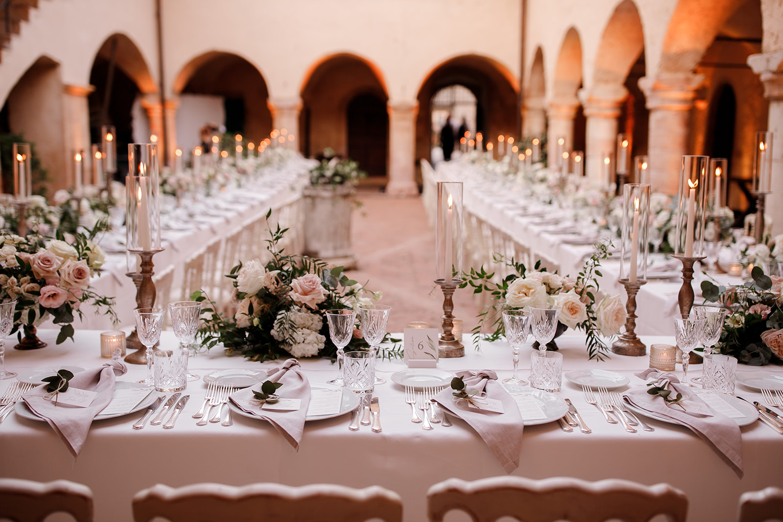 Candlelit long tables under the arches of the cloister at the Abbazia di San Pietro in Valle, Umbria, Denise More