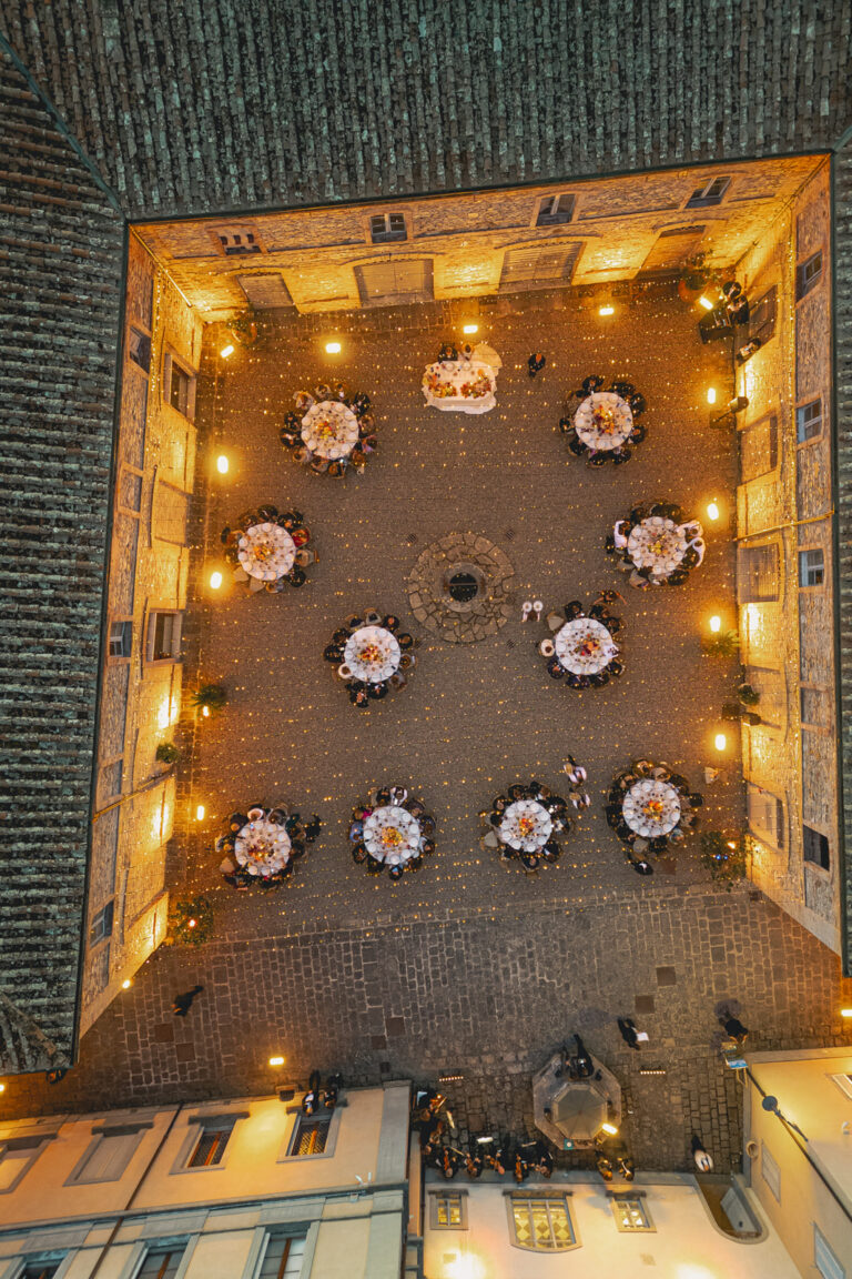 Overhead view of round tables in a lantern-lit courtyard in Tuscany, Denise More
