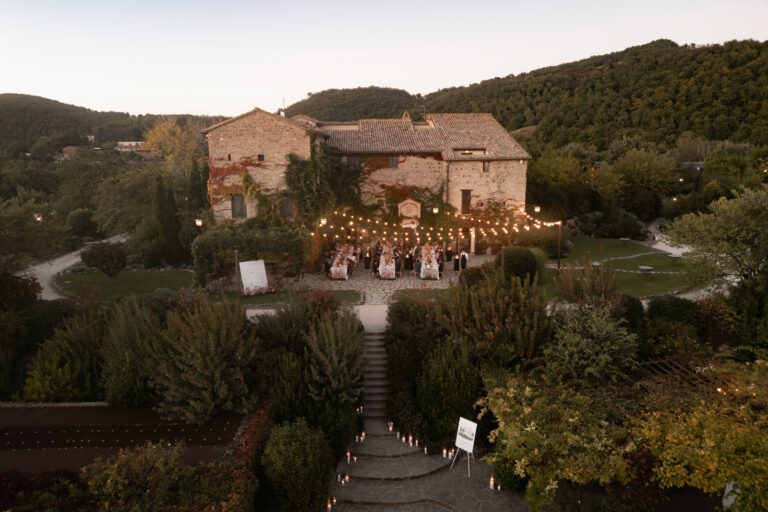 Castello di Petrata at dusk, the dinner lit by festoon lights in the garden below, Denise More