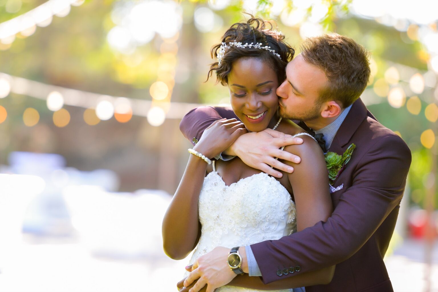 A couple embracing in a garden with festoon lights strung overhead