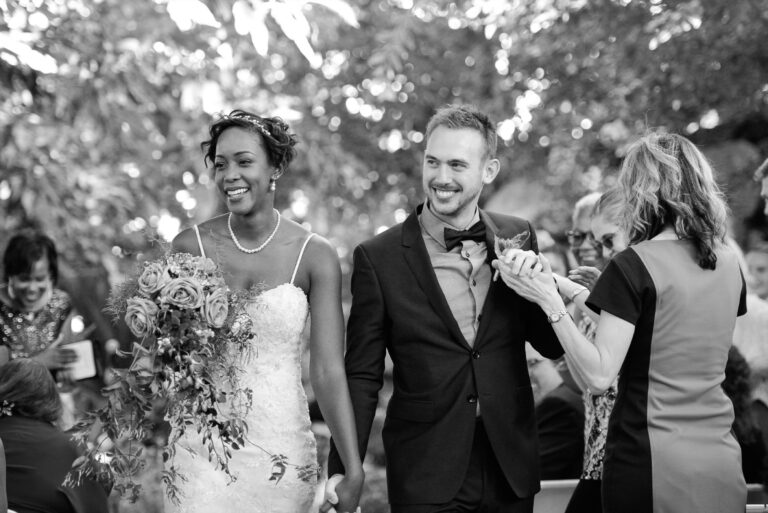 Bride and groom walking among guests in a garden, in black and white, Despina Craig Events