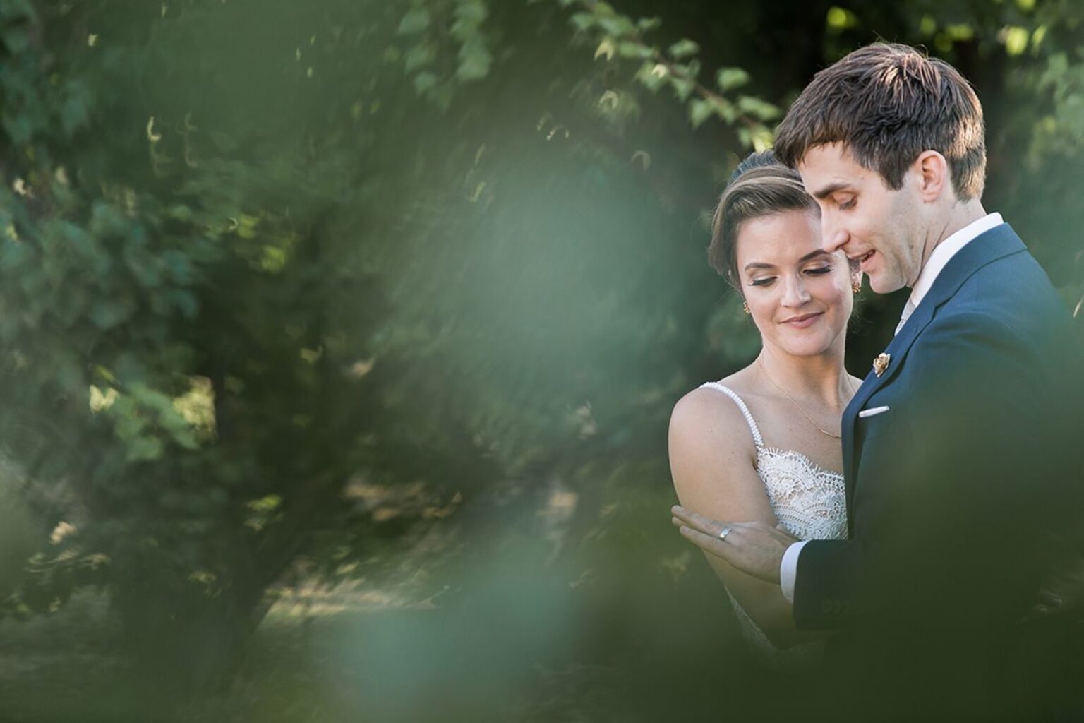 A couple in a quiet embrace among soft orchard foliage