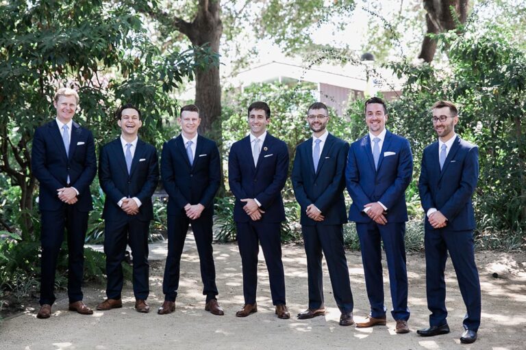 Groomsmen in navy suits lined up beneath orchard trees, Despina Craig Events