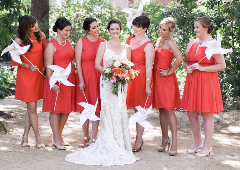 The bride with bridesmaids in coral, each holding a paper pinwheel, Despina Craig Events