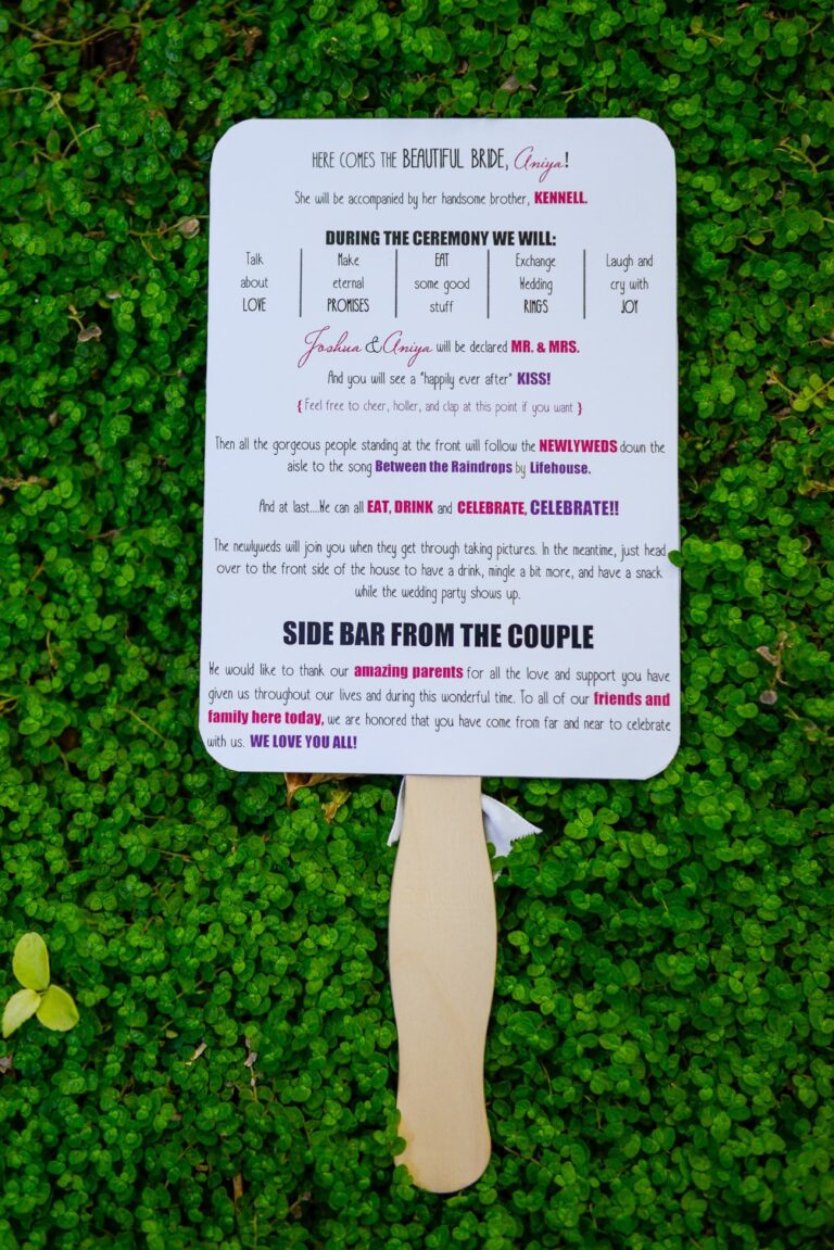 A ceremony programme printed on a paddle fan, laid on greenery, Despina Craig Events