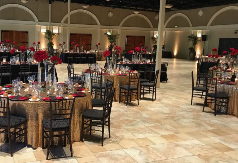 A ballroom set with round tables, gold linens and red floral centrepieces, Despina Craig Events