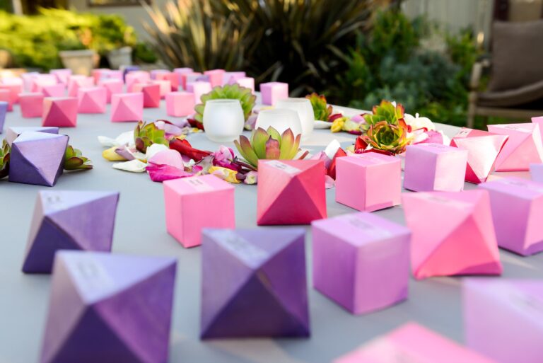 Pink and purple faceted favour boxes scattered along a reception table, Despina Craig Events