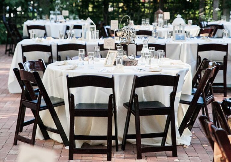 Round tables with ivory linens and dark folding chairs on a brick courtyard, Despina Craig Events